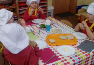 Czworo dzieci przy stoliku degustuje kanapki podczas podwieczorku